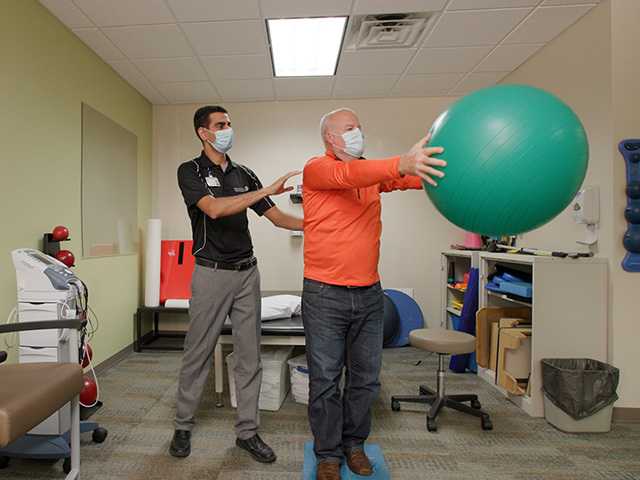 Healthcare provider helping man with Swedish ball.