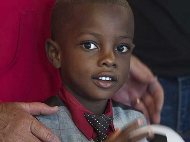 Close-up of smiling boy with adults behind him