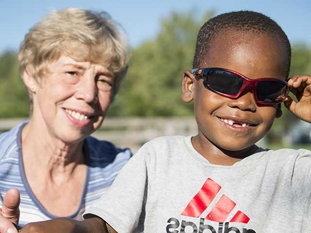 Young boy with sunglasses on in front of an older woman
