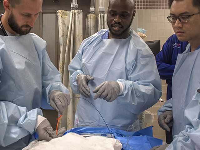 three doctors standing side by side in a trauma room simulation