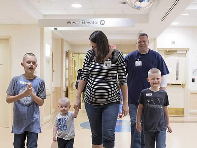 Family with children walks down hospital hallway