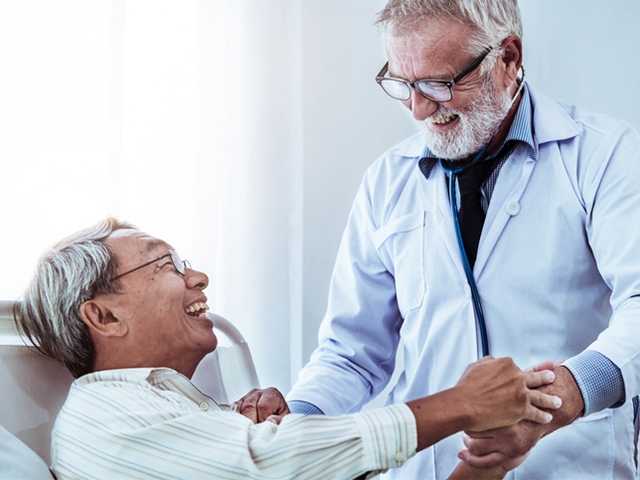 Provider tending to patient in hospital bed.