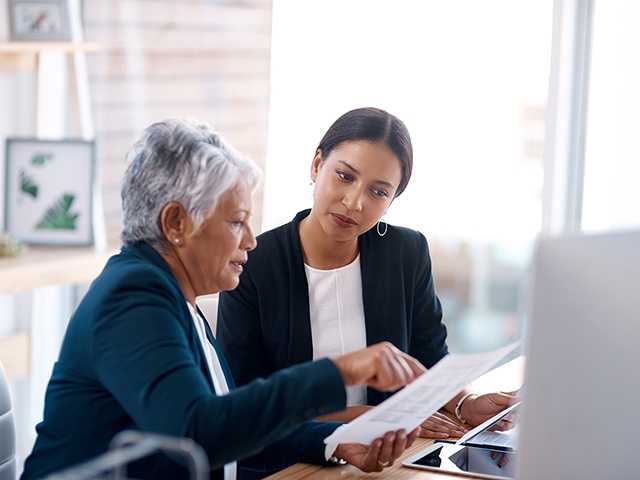 Two women discussing over paperwork.