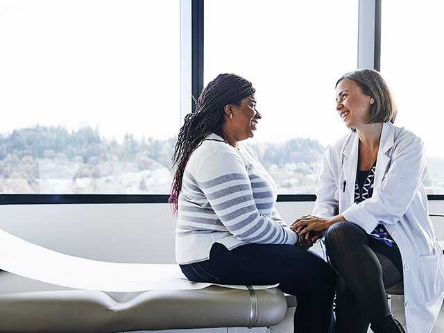Female doctor in white lab coat sitting next to female patient