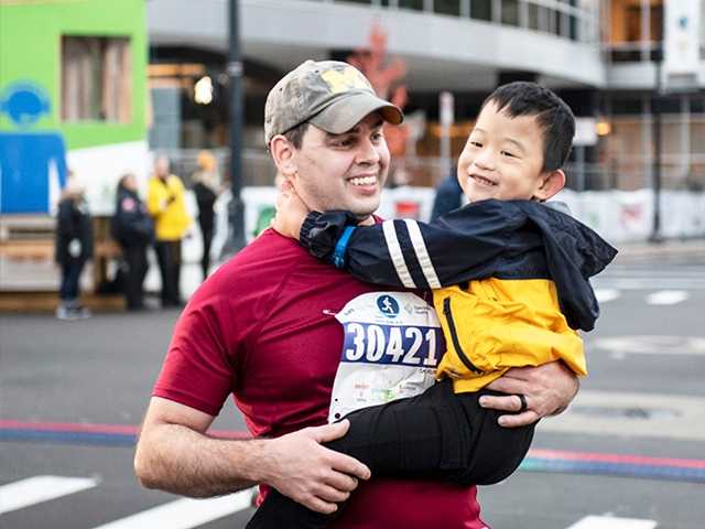 Man in the city holding a young child.