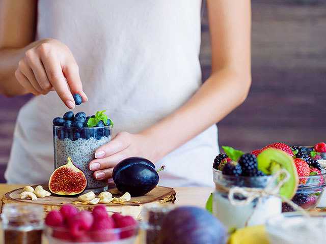 Woman preparing fruit cup.