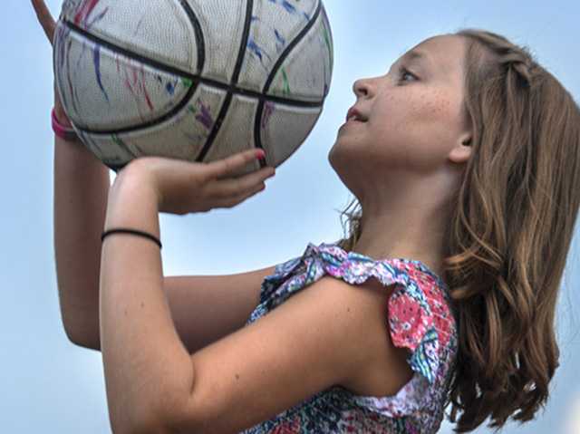 Young girl shooting basketball.