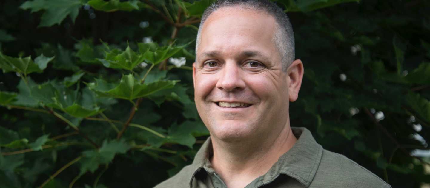 Man standing in front of leaves