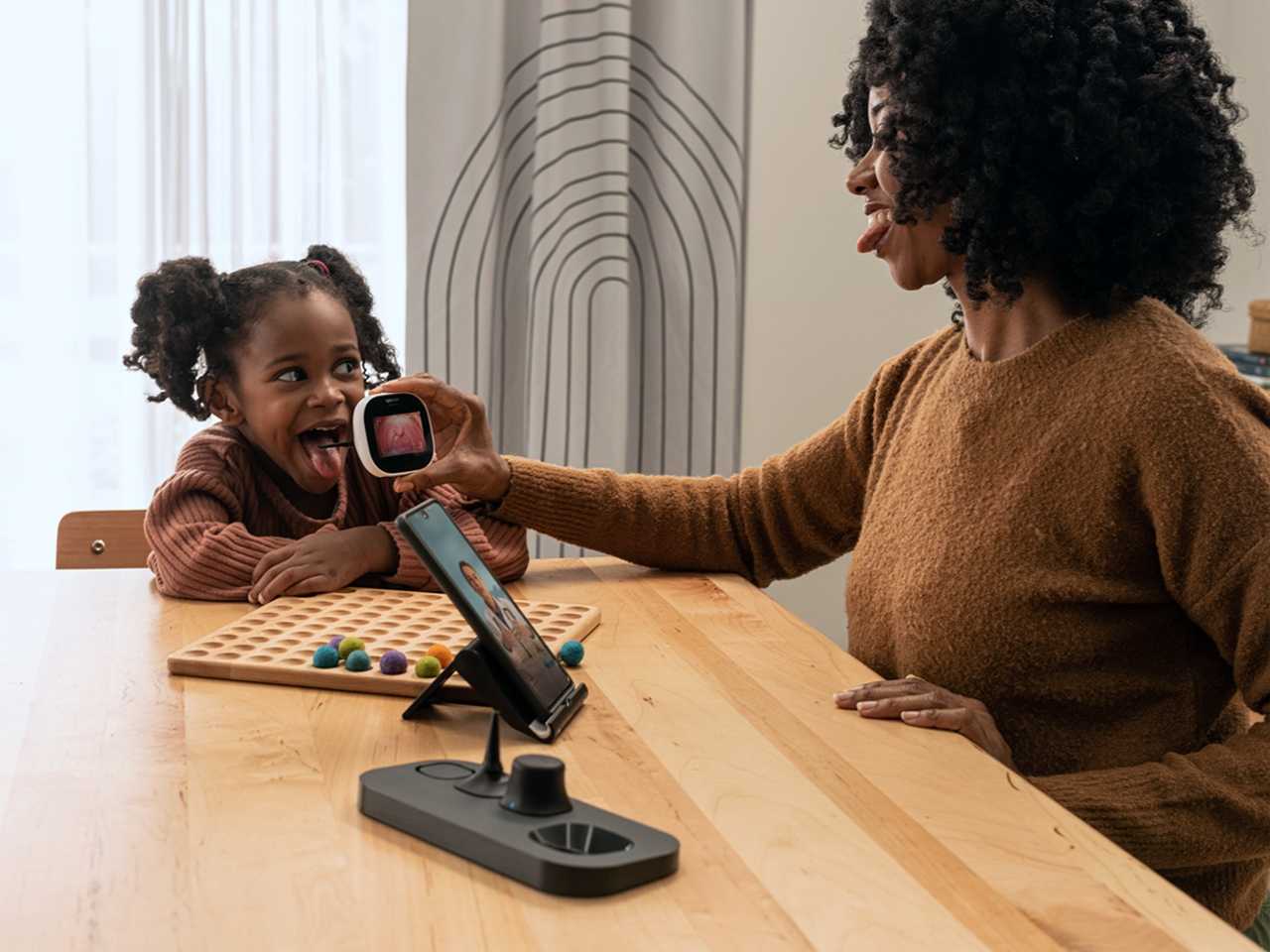 Woman sitting with child, talking to healthcare provider on a laptop.