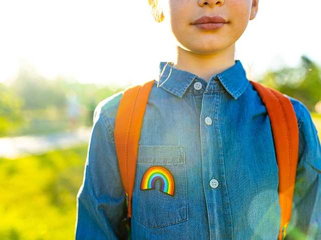 Boy with backpack and rainbow on his shirt.