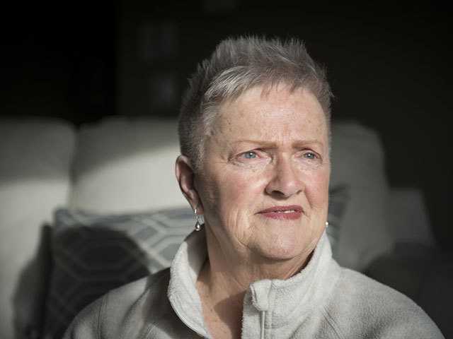 older Caucasian woman with short grey hair standing in sunlight