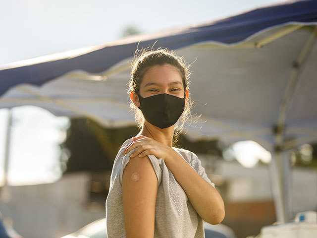 Girl showing upper arm with small bandaid.