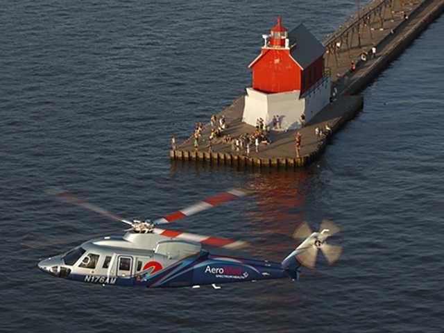aero med helicopter flying over water with lighthouse in the background