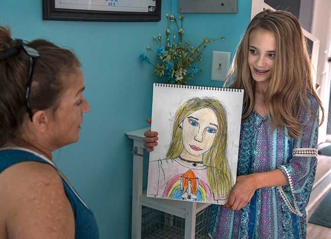 Child showing drawing to woman.