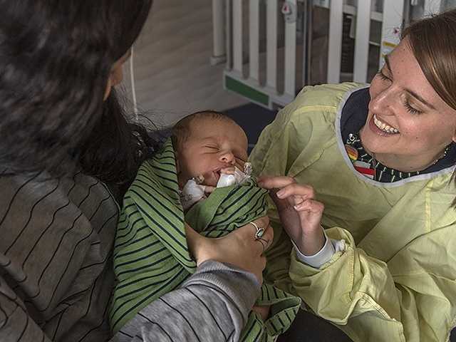 Mother holding baby while another woman visits.