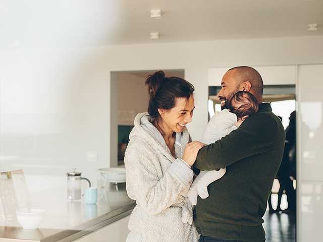 Man holding baby in front of woman in robe.