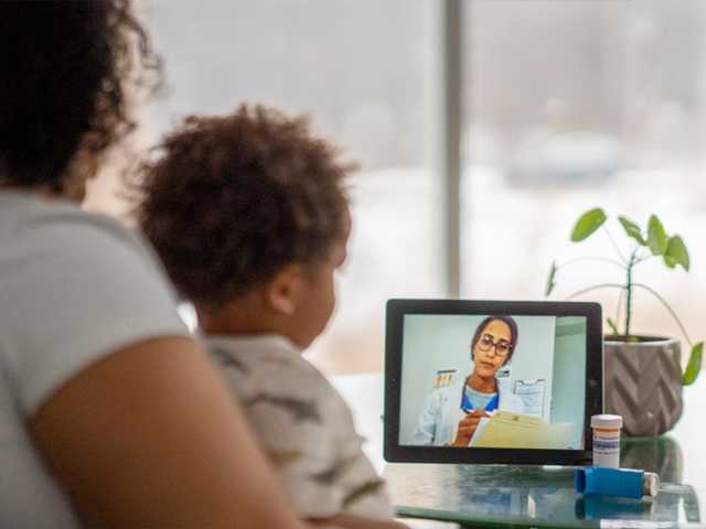 Woman and child sitting in front of tablet, talking to healthcare provider.