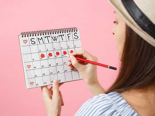 woman holding a calendar while in front of pink wall