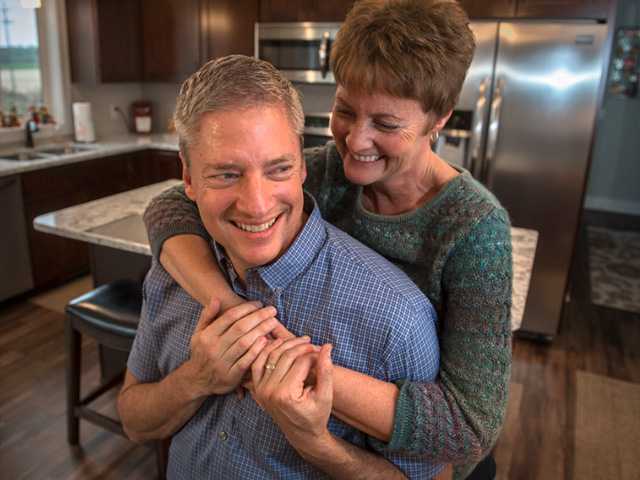 Woman holding embracing man from behind.