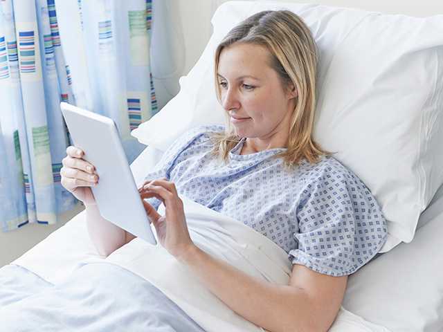 Woman holding a tablet in a hospital bed