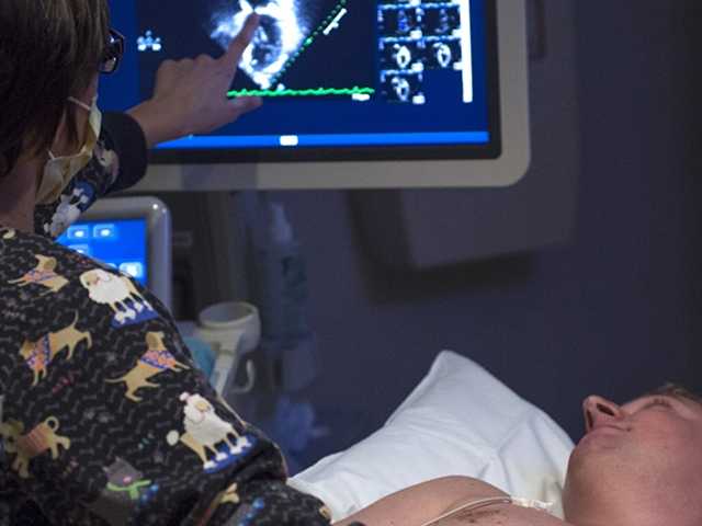 Healthcare provider performing imaging scan on patient in bed.