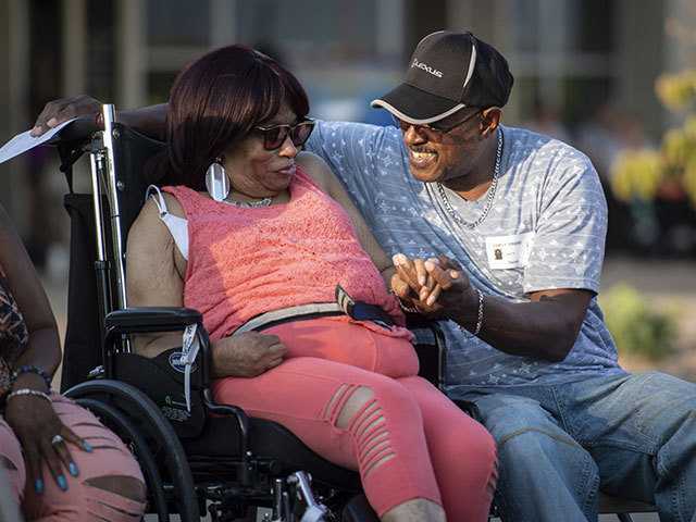 Man holds hand of woman in wheelchair
