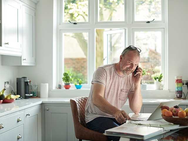 Man talking on cellphone in front of laptop.