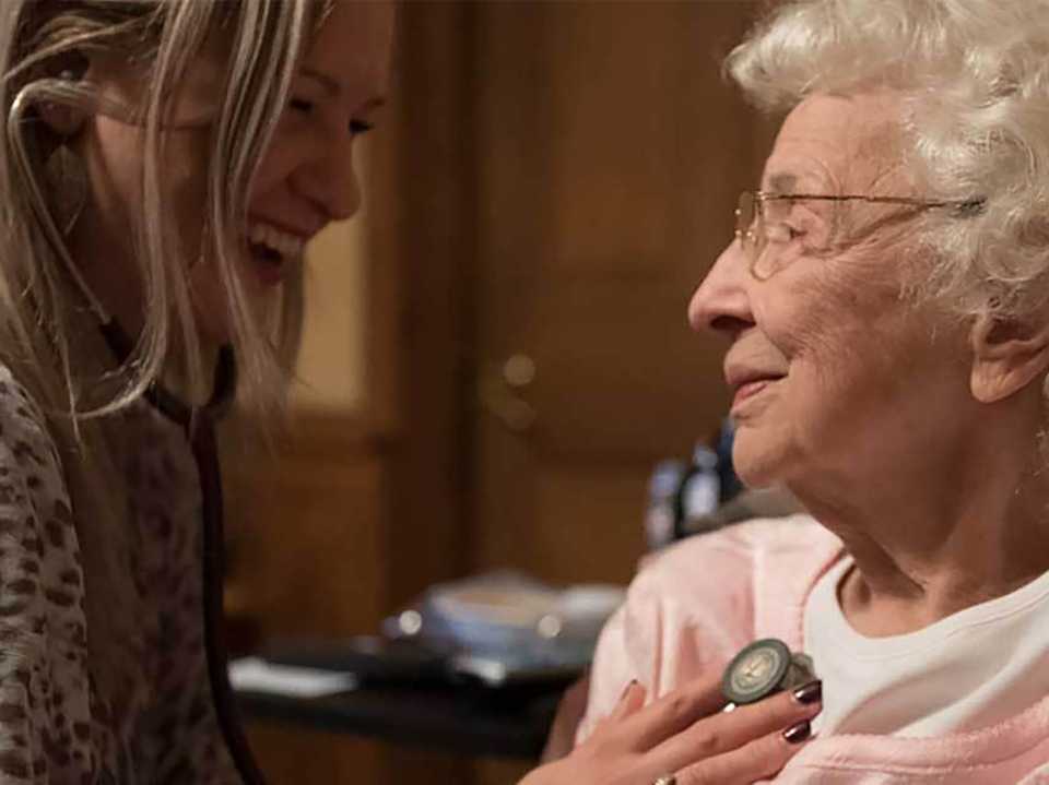 Healthcare provider listening to senior woman's heart.