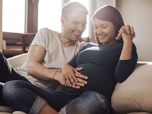 Man with hand on woman's pregnant belly.