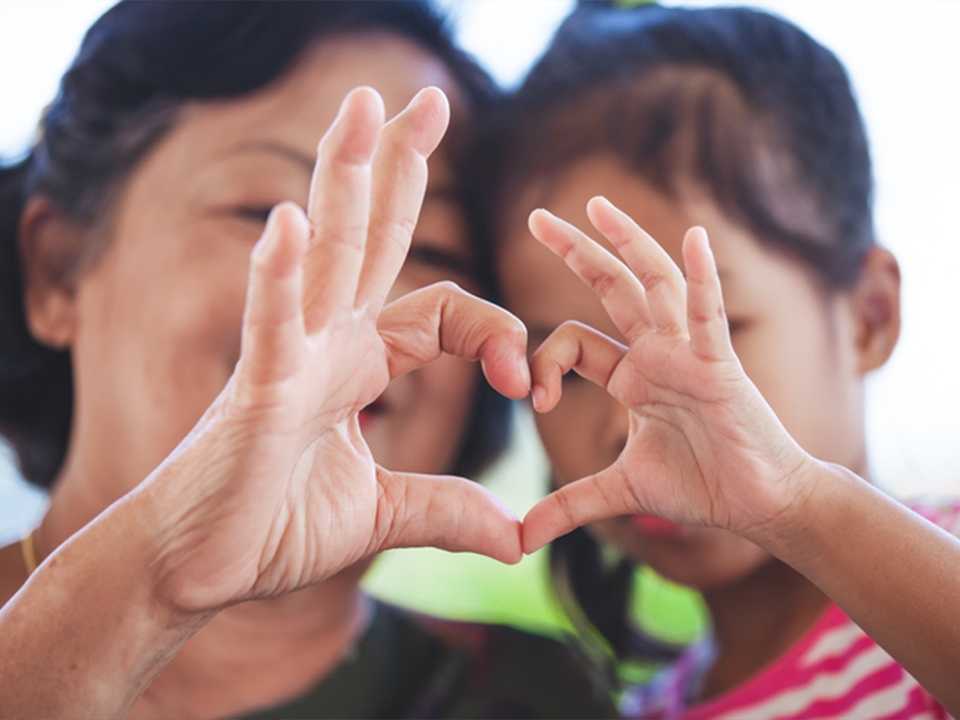 Woman and child making heart symbol with hands.